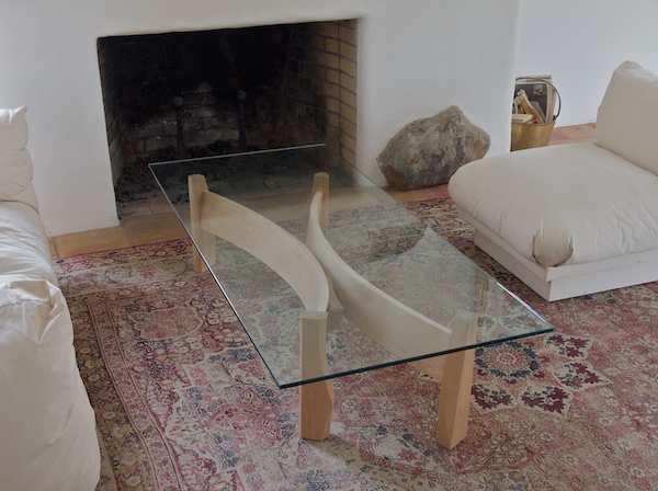 Glass topped coffee table with two sweeping curves and a decorative piece connecting them together